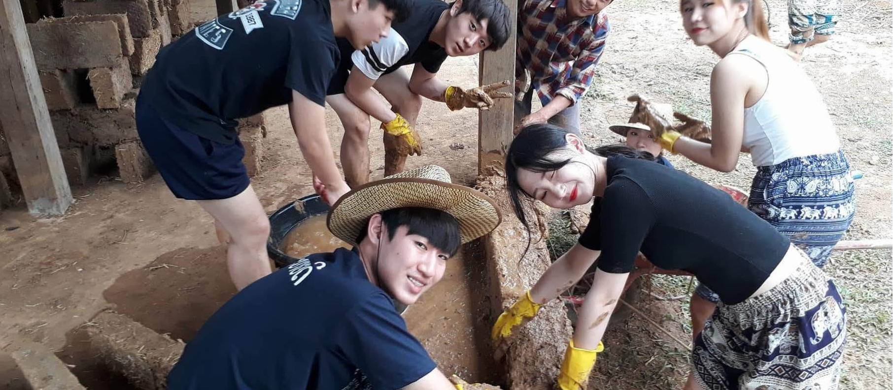 Students building a wall using Adobe bricks