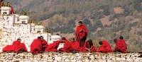 Bhutanese monks socialise along the monastery wall | Liz Light