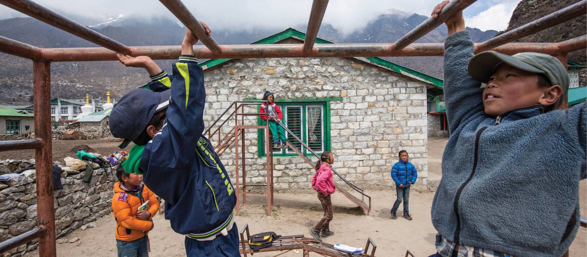 Local children playing on the monkey bars at Khumjung school | Mark Tipple
