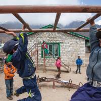 Local children playing on the monkey bars at Khumjung school | Mark Tipple
