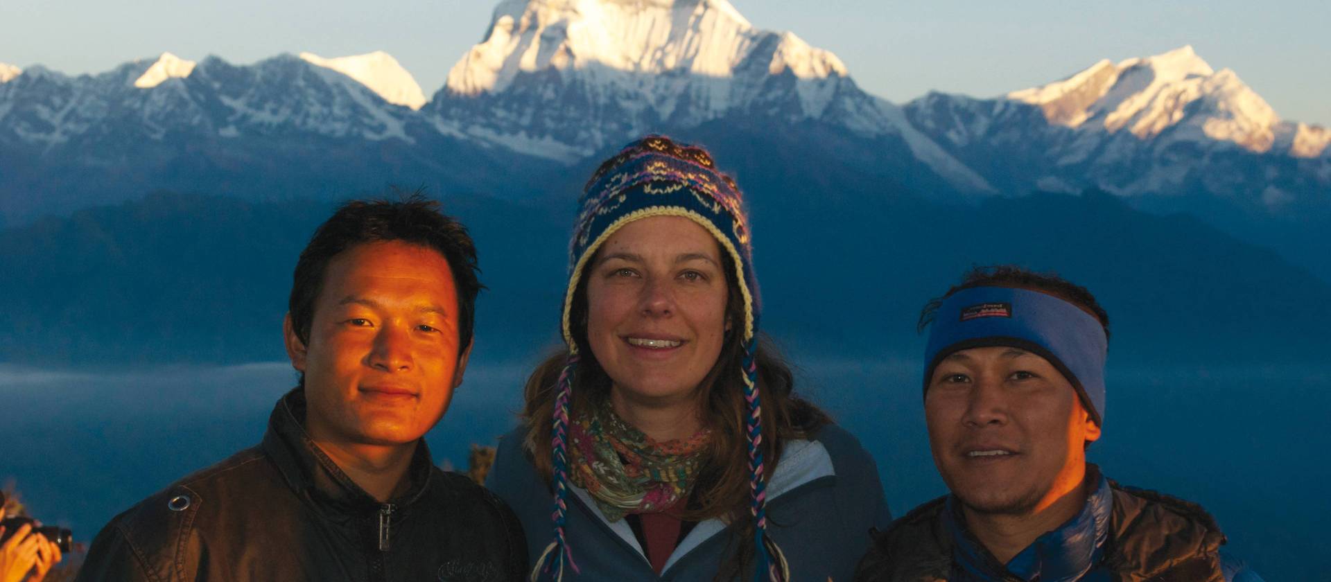Local Nepali staff and happy trekker enjoy sunrise at Poon Hill, Annapurna region | Carlie Ballard