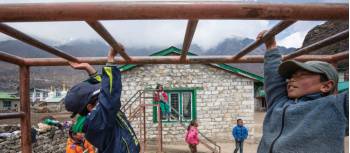 Local children playing on the monkey bars at Khumjung school | Mark Tipple